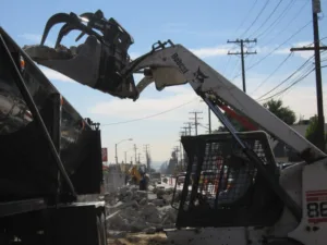 bobcat dropping concrete debris in dumpster